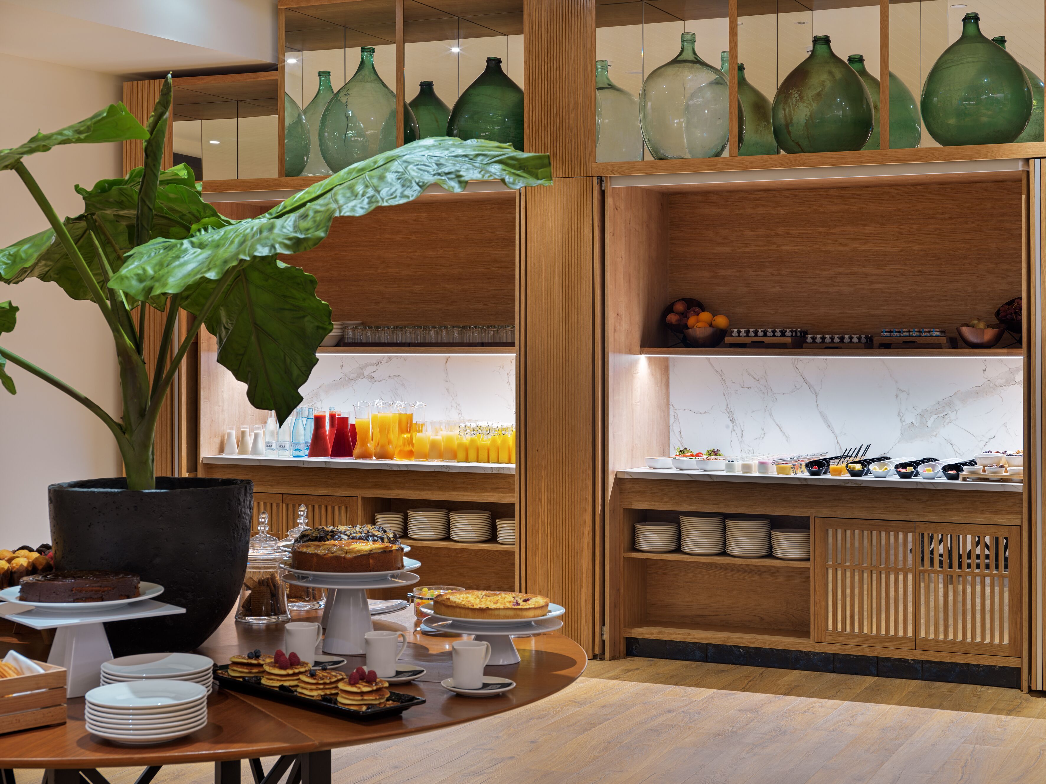 Buffet de l'esmorzar amb diversos aliments i una gran planta en test.