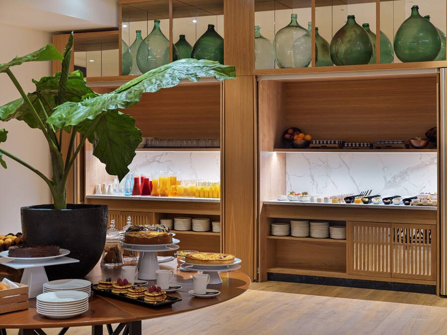 Buffet de l'esmorzar amb diversos aliments i una gran planta en test.