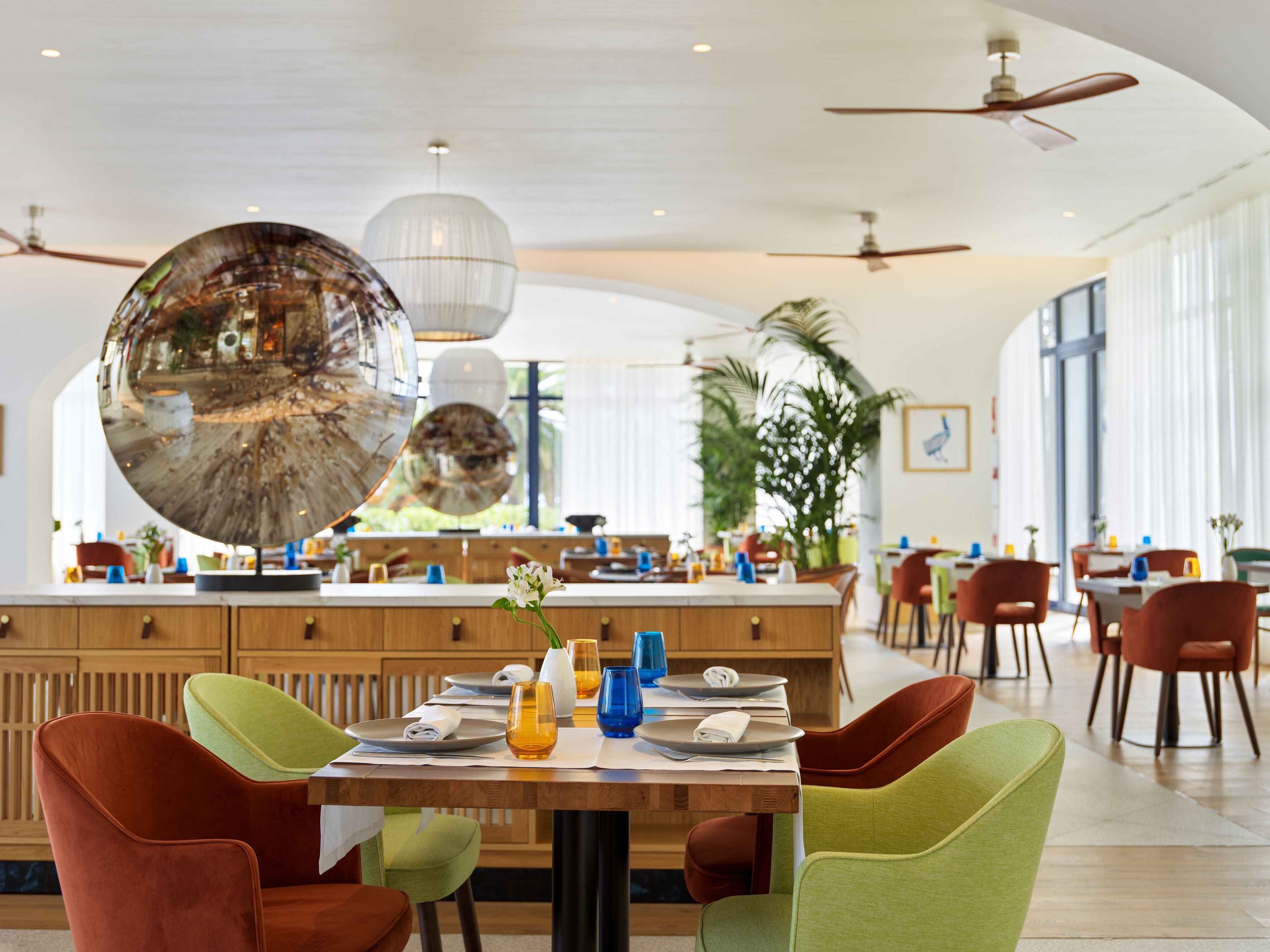 A modern dining area with a central island, multiple seating options, and ceiling fans.