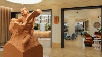 Eine moderne Hotelhalle mit einer großen Skulptur, Sitzbereichen und einer Rezeption.