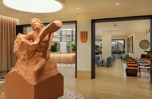 Un lobby moderno de hotel con una gran escultura, zonas de estar y un mostrador de recepción.