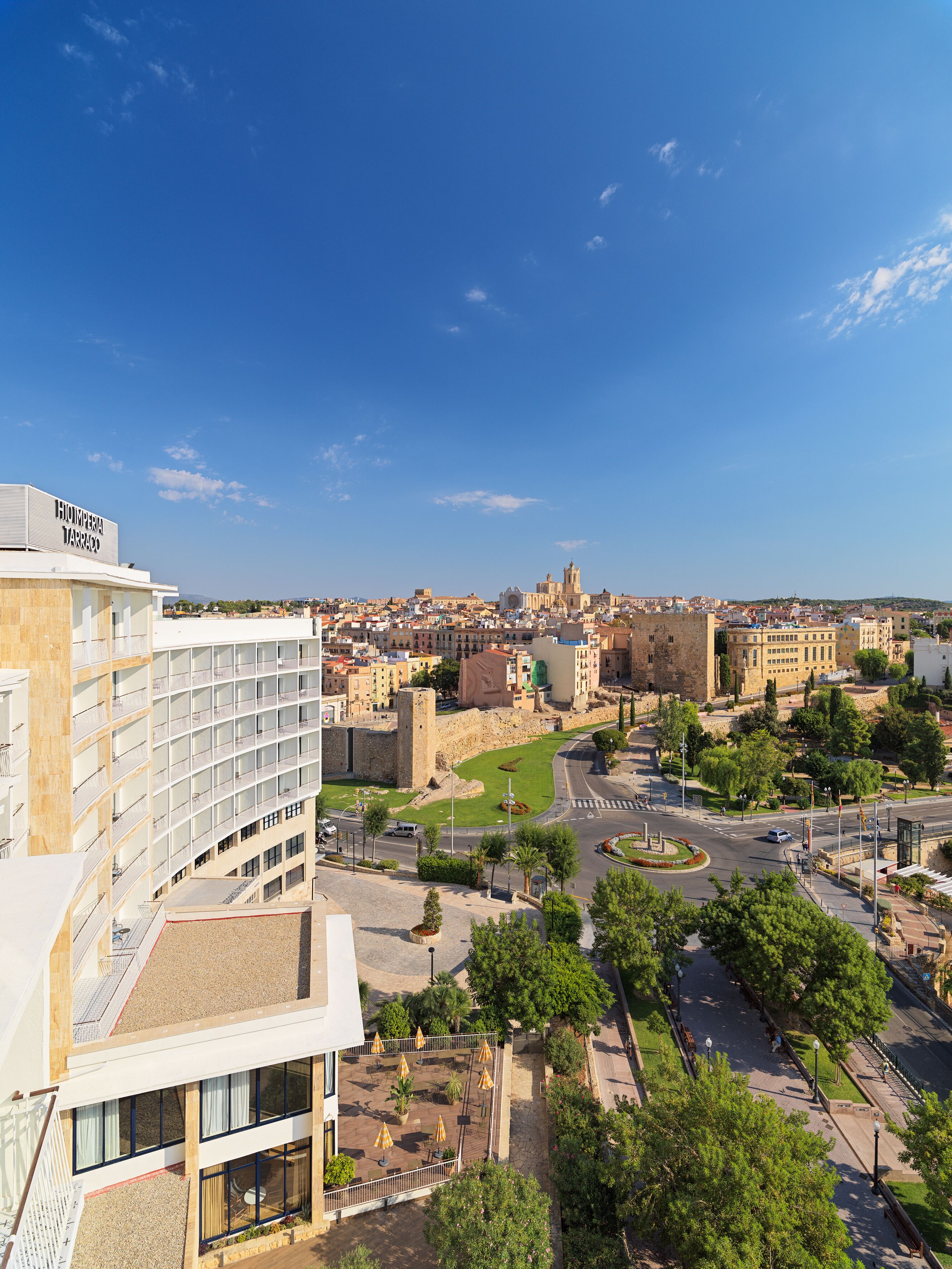 Un hotel de diseño moderno, con terraza en la azotea y mobiliario exterior, incluyendo sombrillas.