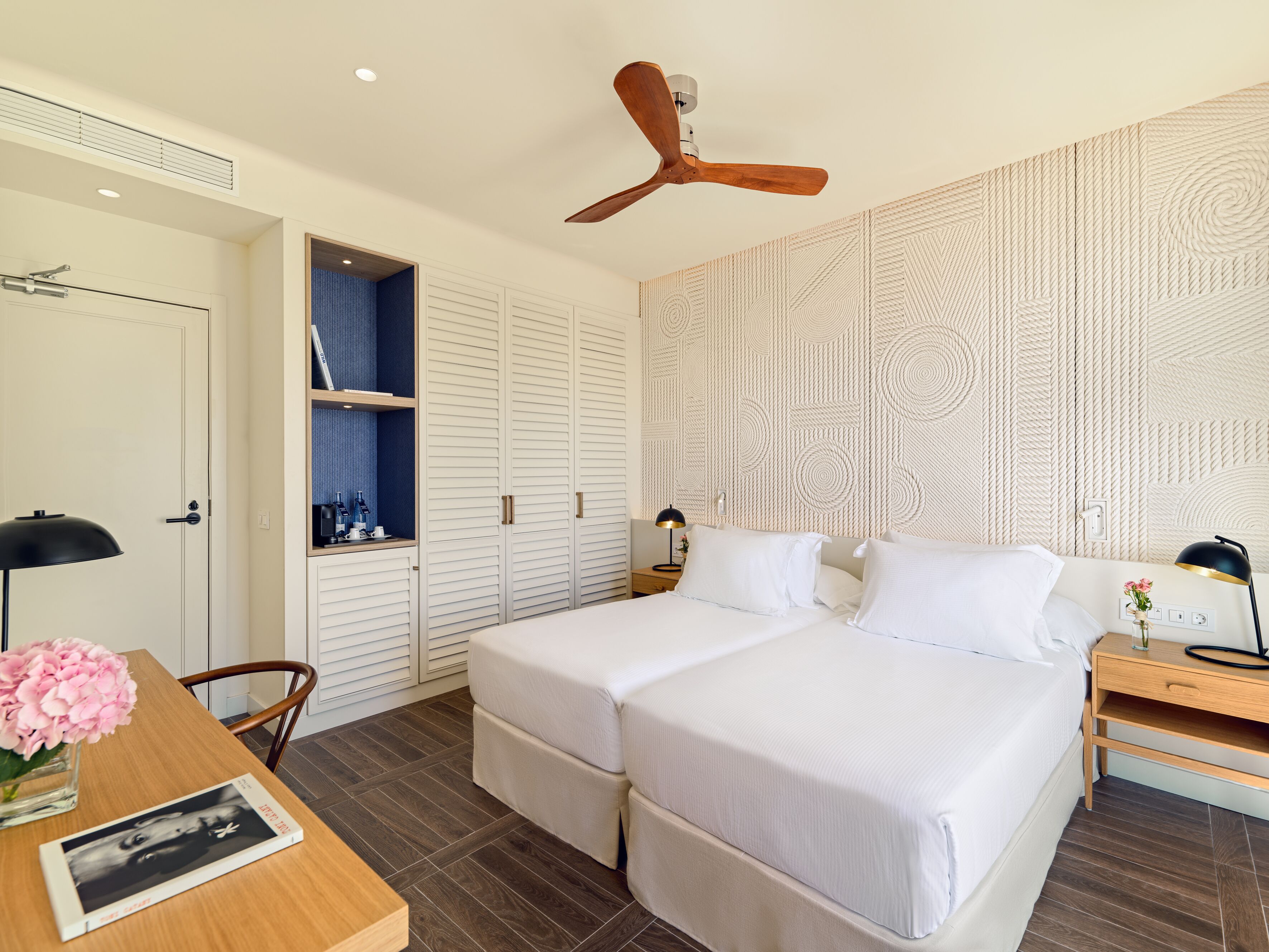 Un dormitorio moderno con una cama grande, un armario y un escritorio con una lámpara y un libro.