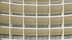 Een meerlaags hotel met een centrale ingang, balkons en een bord waarop 