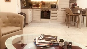 Cocina moderna con comedor, sofá y una mesa de centro de vidrio con revistas y una planta.