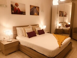 Un dormitorio con cama, mesitas de noche, espejo y decoración en la pared.