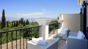 A balcony with wicker furniture, a view of the sea, and a mountainous landscape. - Villa Fedra (Corfu)