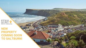 A coastal town with a cliff, beach, and a crowd of people. - Caedmon Prospect (Whitby)