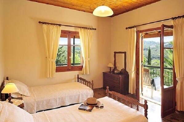 A bedroom with two beds, a dresser, and a window with curtains.