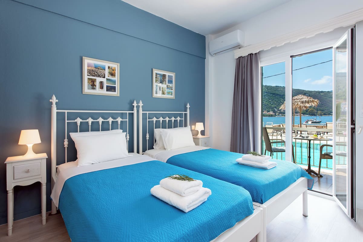 Ein Hotelzimmer mit zwei Betten, einem Balkon mit Blick auf den Pool und einem weißen Bettgestell.