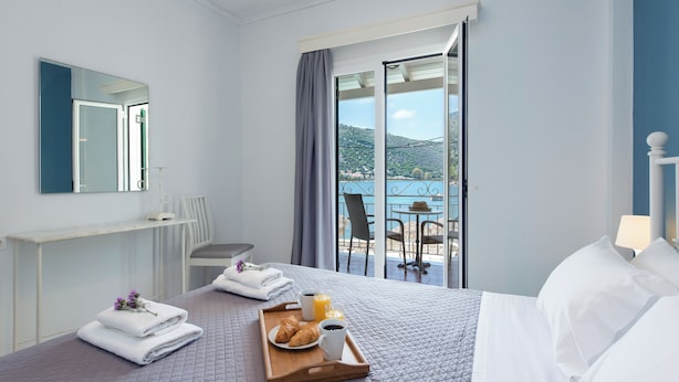 Een hotelkamer met een bed, een ontbijttafel en uitzicht op zee.