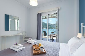 A hotel room with a bed, breakfast tray, and a view of the sea.