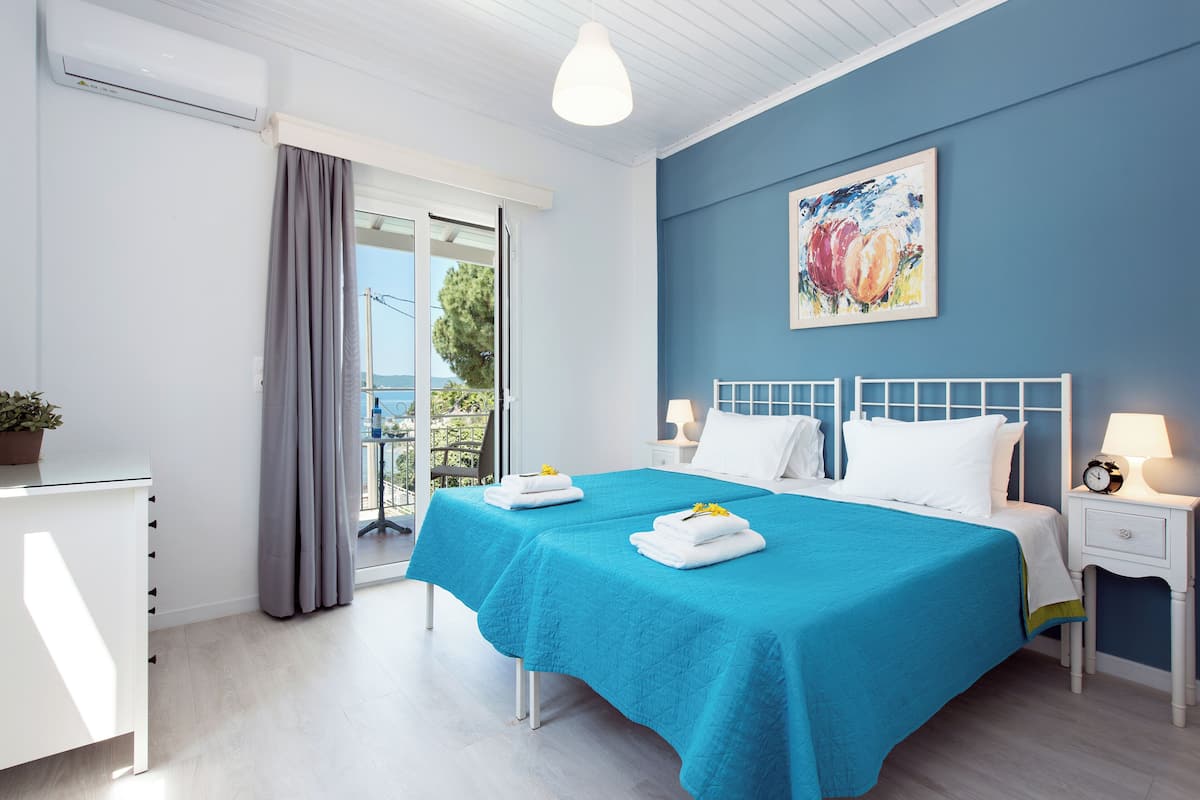 Ein Schlafzimmer mit zwei Betten, einer weißen Kommode, einem Nachttisch und einem Bild an der Wand.