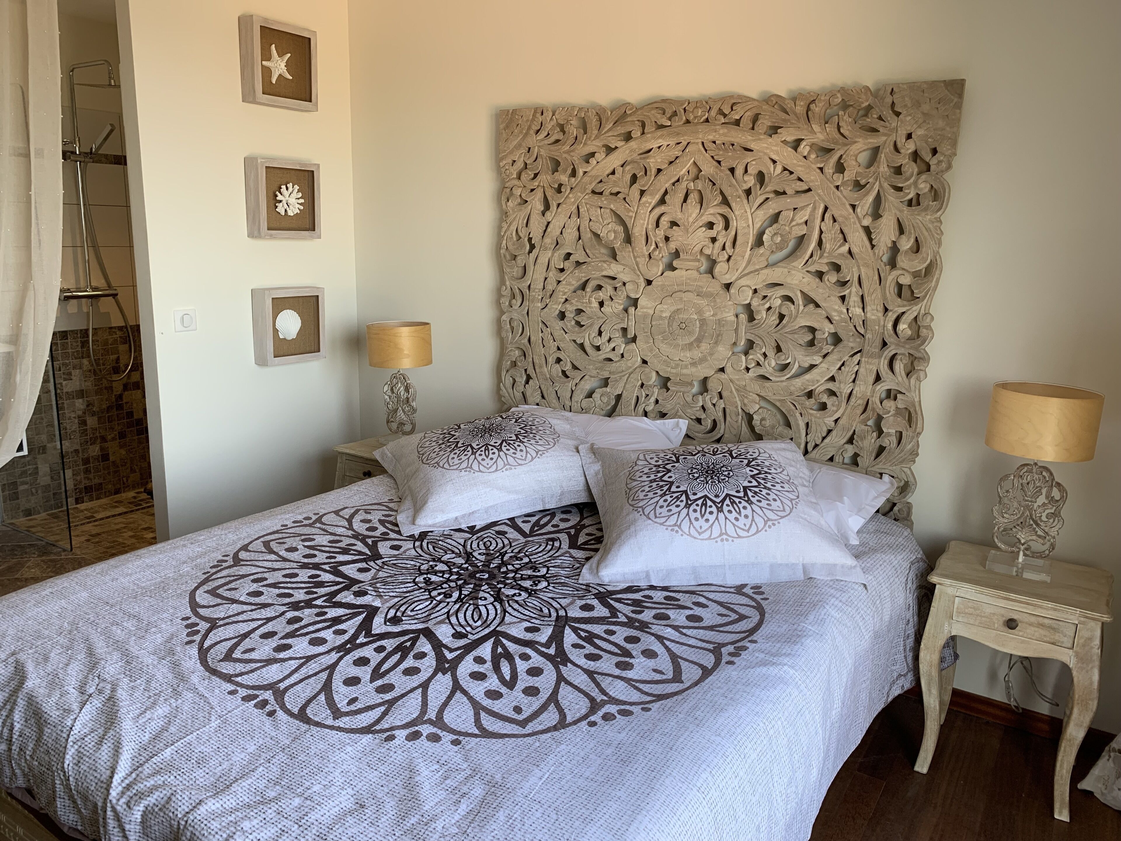 Une chambre à coucher avec un grand lit, une tête de lit décorée et deux tables de chevet avec des lampes.