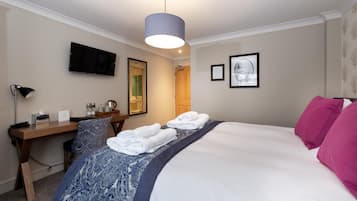 Een hotelkamer met een bed, een bureau, een stoel, een televisie en een spiegel.