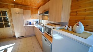 Una cocina con armarios de madera, microondas, estufa y fregadero.