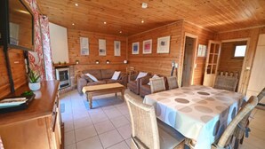 Interior de una cabaña de madera con sofá, una mesa de comedor y una cama.