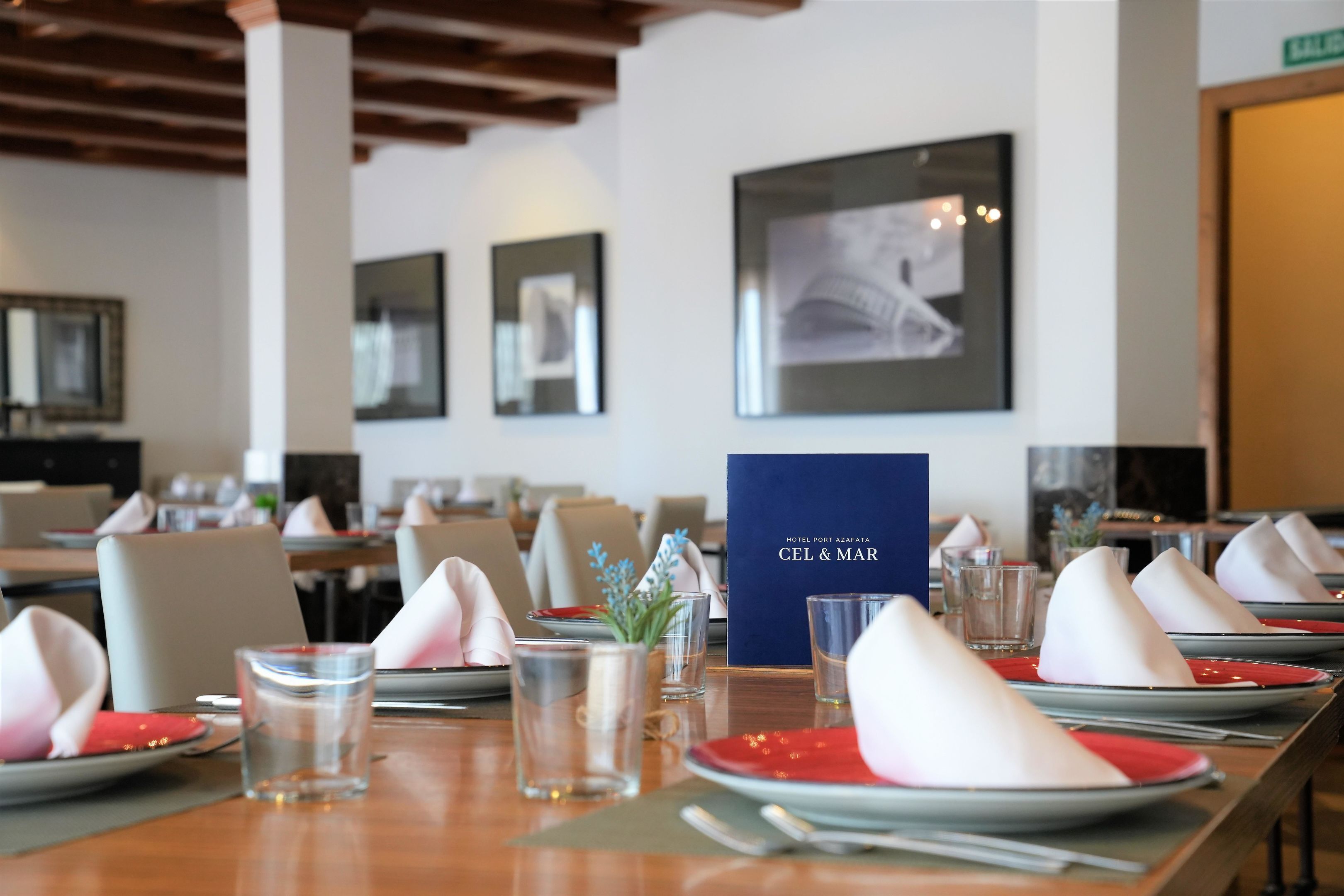 A dining area with tables set for a meal, including plates, napkins, and glasses.