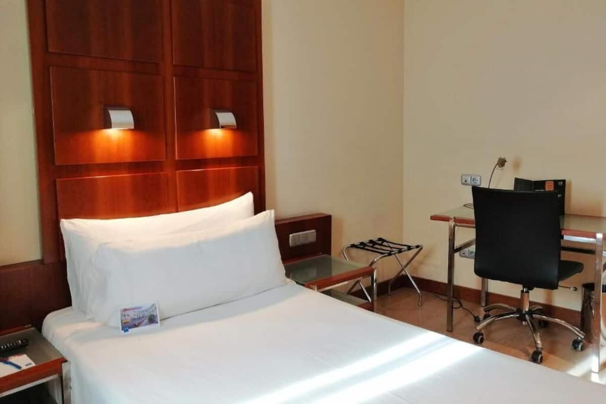 Een hotelkamer met een bed, een bureau en een stoel.