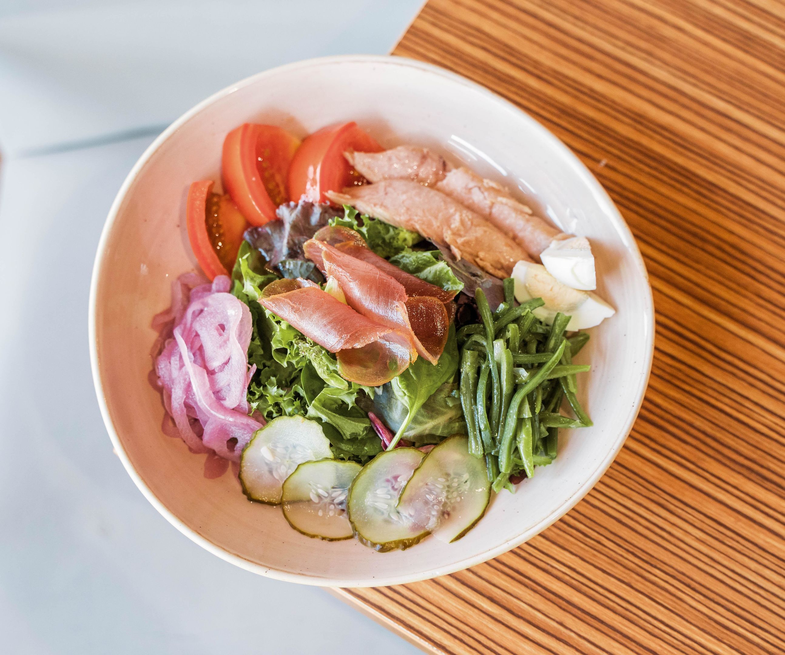 A bowl of salad with various vegetables and meats.