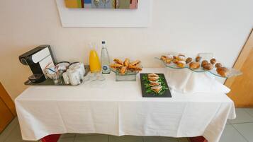 Una mesa de buffet con diversos alimentos, una botella de agua y una máquina de café.