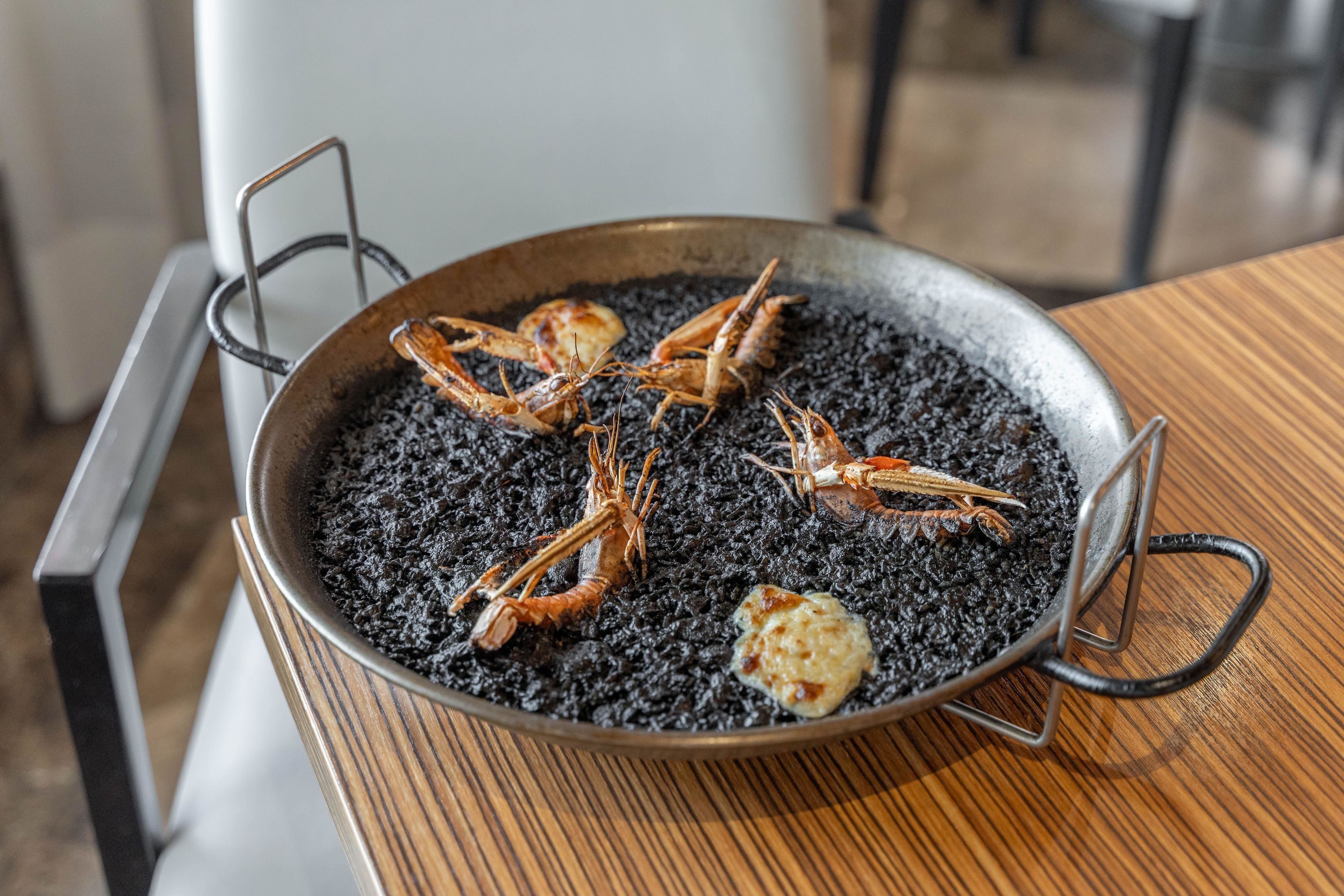 Una paellera con mariscos sobre una mesa de madera.