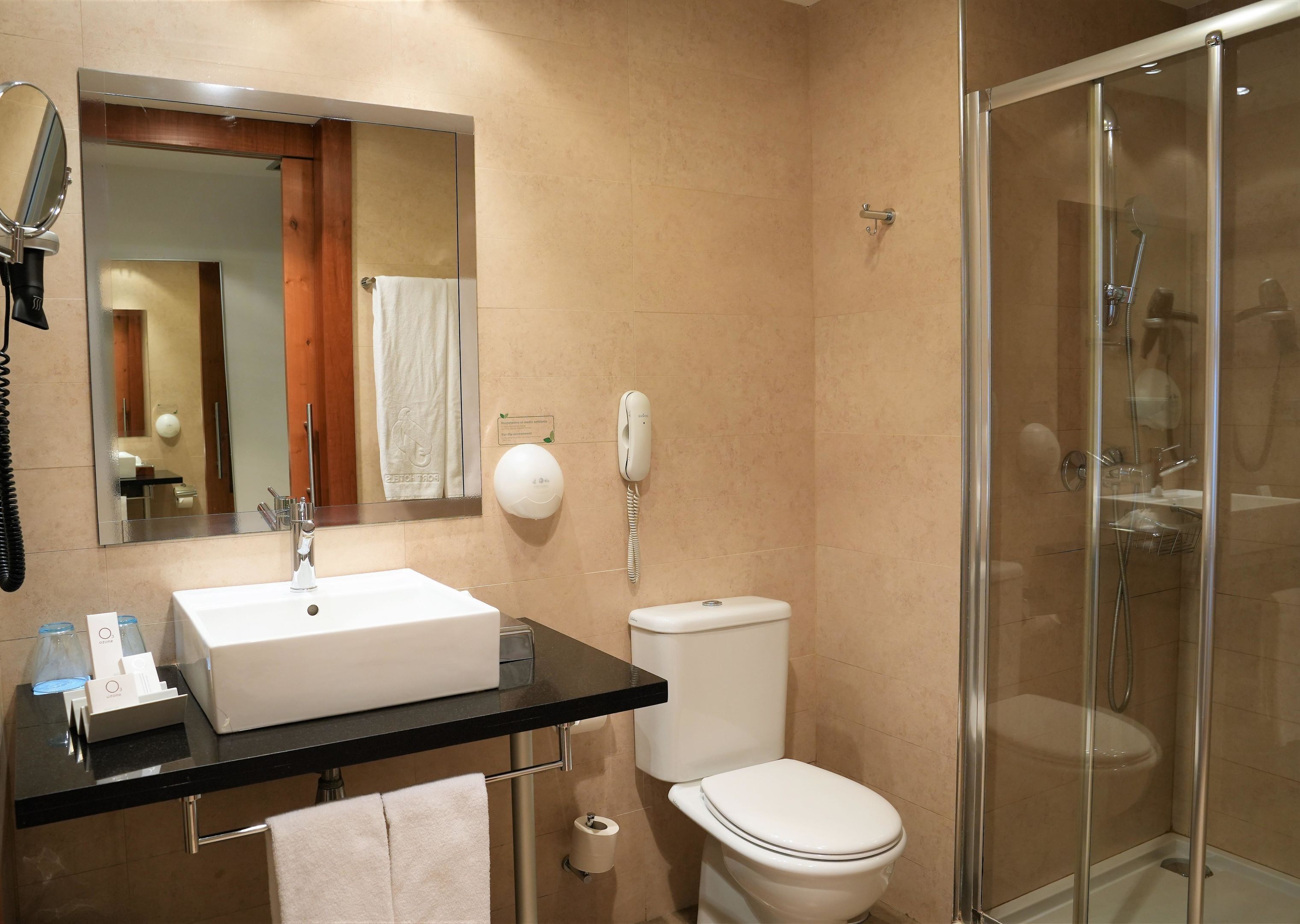 Un bagno moderno con uno specchio grande, un lavandino bianco, un water e una doccia con pareti in vetro.
