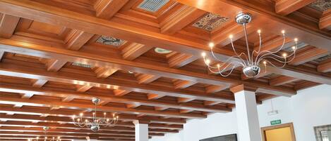 A hotel interior with wooden ceiling beams and chandeliers.