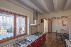 A kitchen with a gas stove, double sink, and a dining area with a table and chairs.