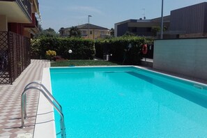 Una piscina rectangular con suelo a cuadros que lleva a una escalera metálica.