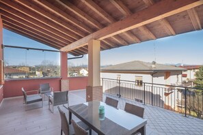 Un patio techado al aire libre con una mesa y sillas, vista de los alrededores y cielo despejado.