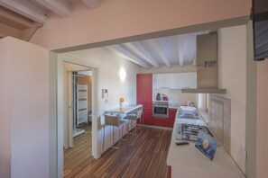 A modern kitchen with a red accent wall, a built-in oven, and a gas stove.