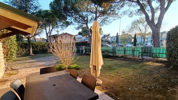 An outdoor patio with a table and chairs, a pergola, and a covered umbrella.