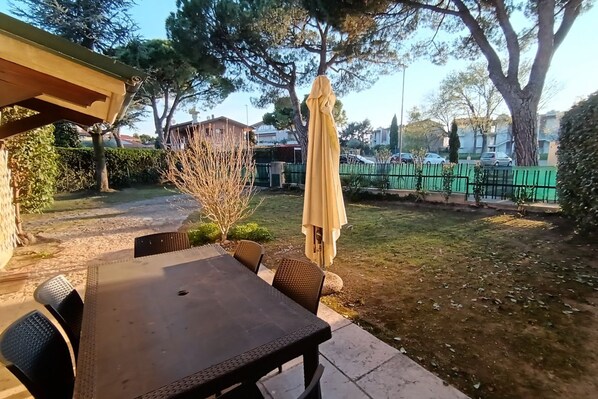 Un patio al aire libre con mesa y sillas, una pérgola y una sombrilla.