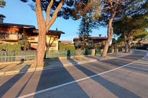 A residential street with houses, trees, and a clear sky.