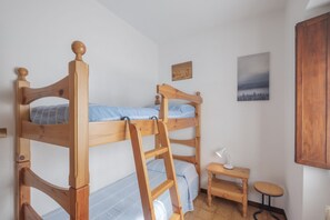 A bunk bed room with a ladder, a small table, and a wall-mounted lamp.