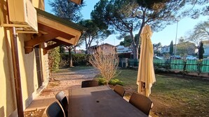 An outdoor patio with a table and chairs, a covered area, and a view of a residential street.