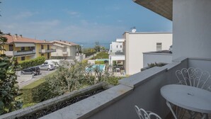 A residential balcony with a view of a body of water, a swimming pool, and neighboring houses.