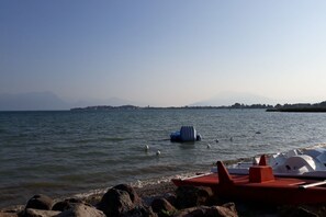 A lakeside view with boats docked near a rocky shore.