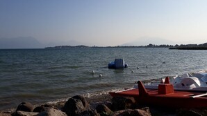 A lakeside view with boats docked near a rocky shore.