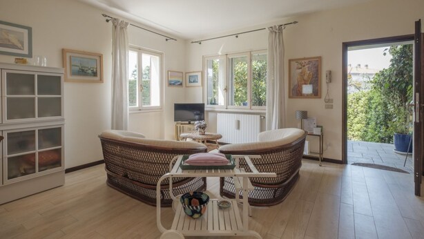 Un salón acogedor con muebles de mimbre, un televisor y vistas al verde exterior.