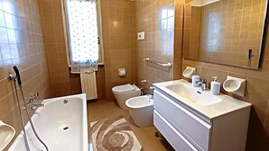 Un baño con bañera, inodoro, bidé, lavabo y espejo.