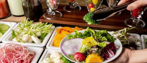 Un bufé con diversos alimentos, como verduras, frutas y ensaladas.