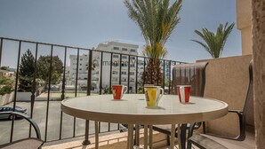 Un balcon avec une table ronde, deux chaises et deux tasses.