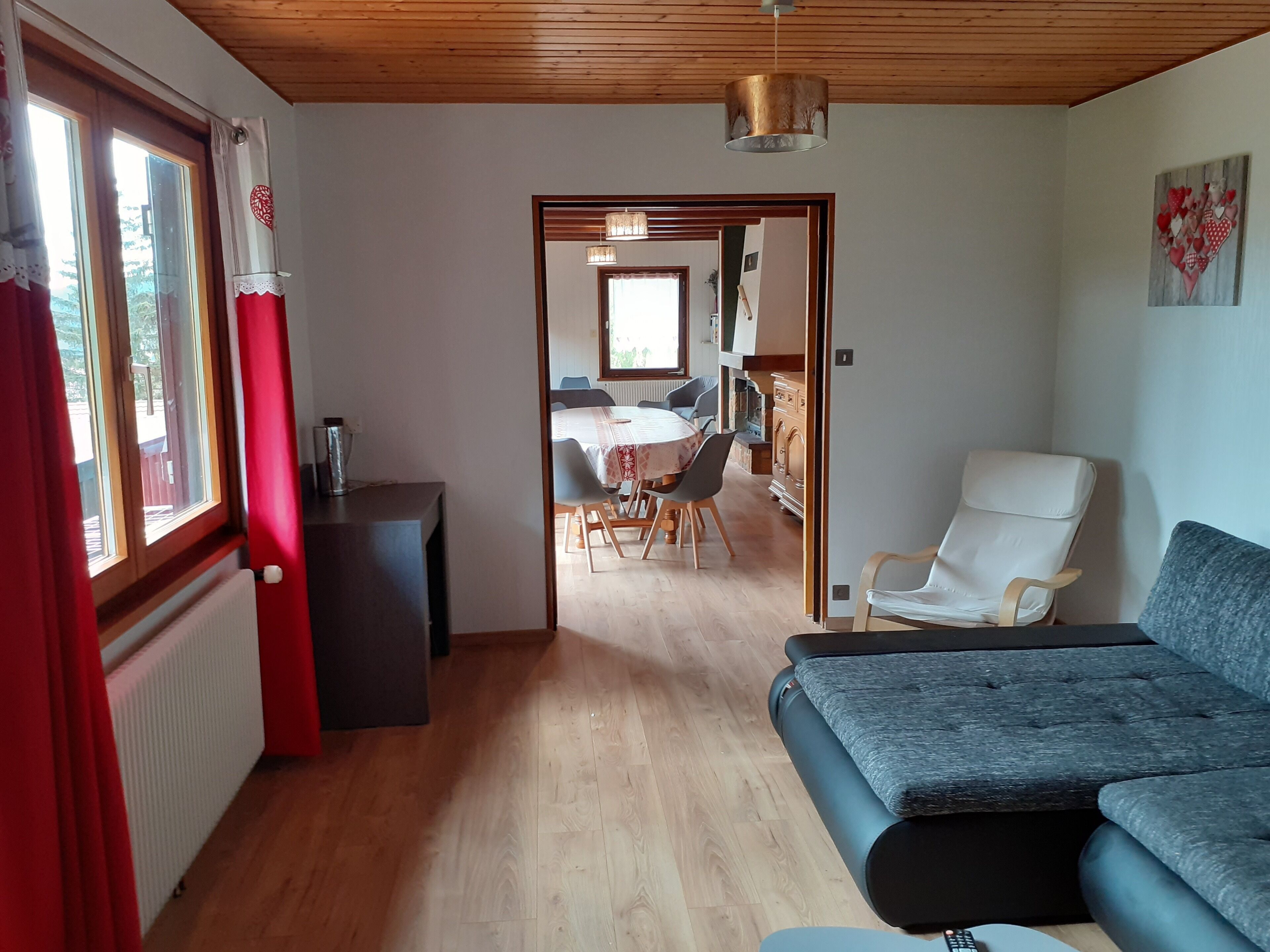 Un salon moderne avec un canapé, un coin repas comprenant une table et des chaises, et une cuisine en arrière-plan.