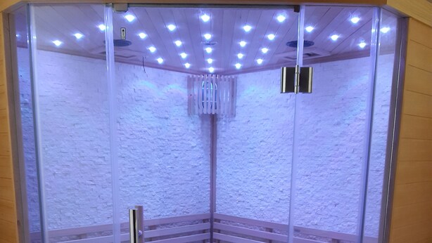 A glass-walled sauna with a wooden bench and a small sink. - Family chalet with sauna for 10-12 people (Gérardmer)