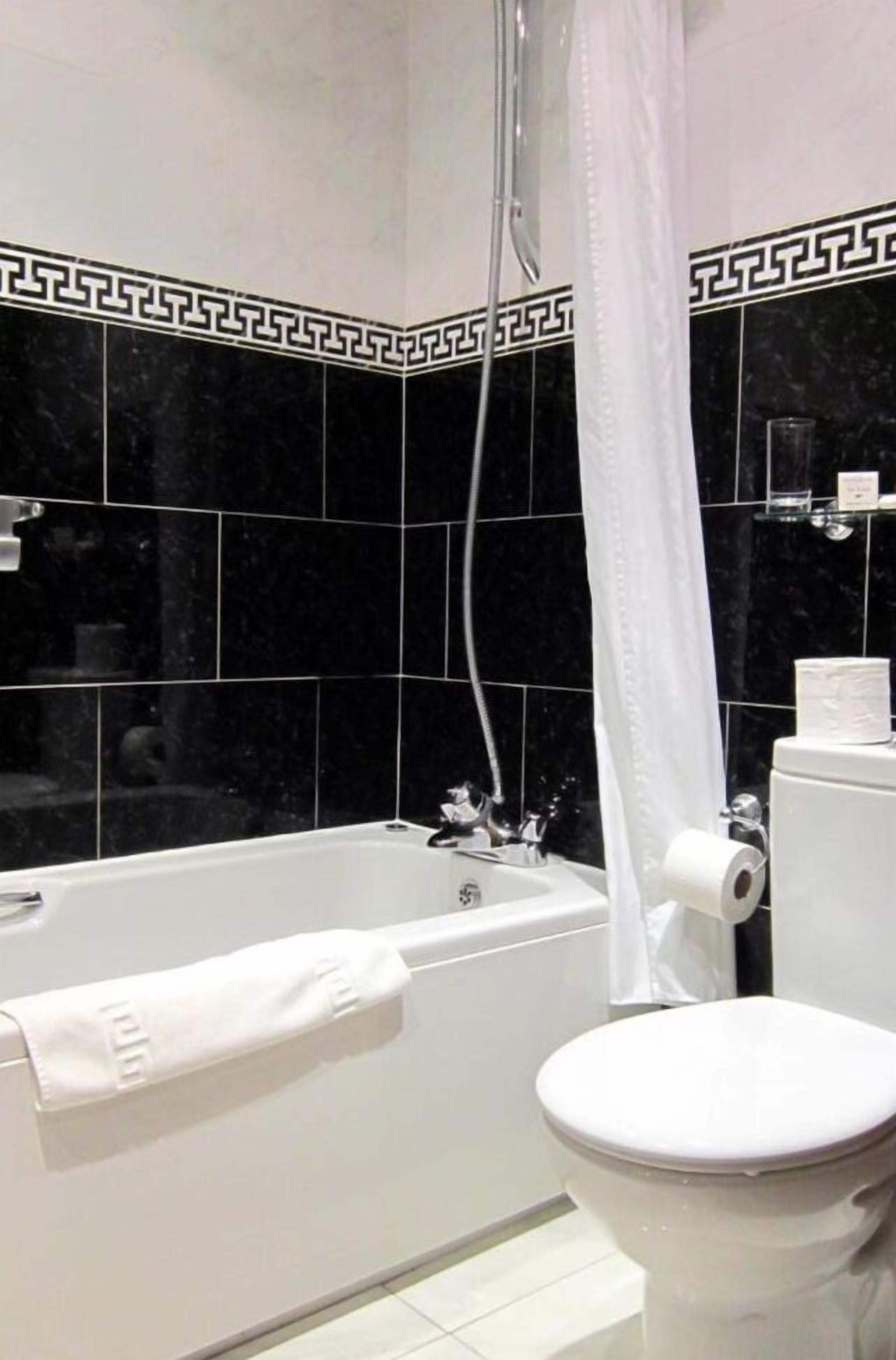 A bathroom with a bathtub, toilet, and shower curtain.