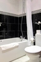 A bathroom with a bathtub, toilet, and shower curtain.