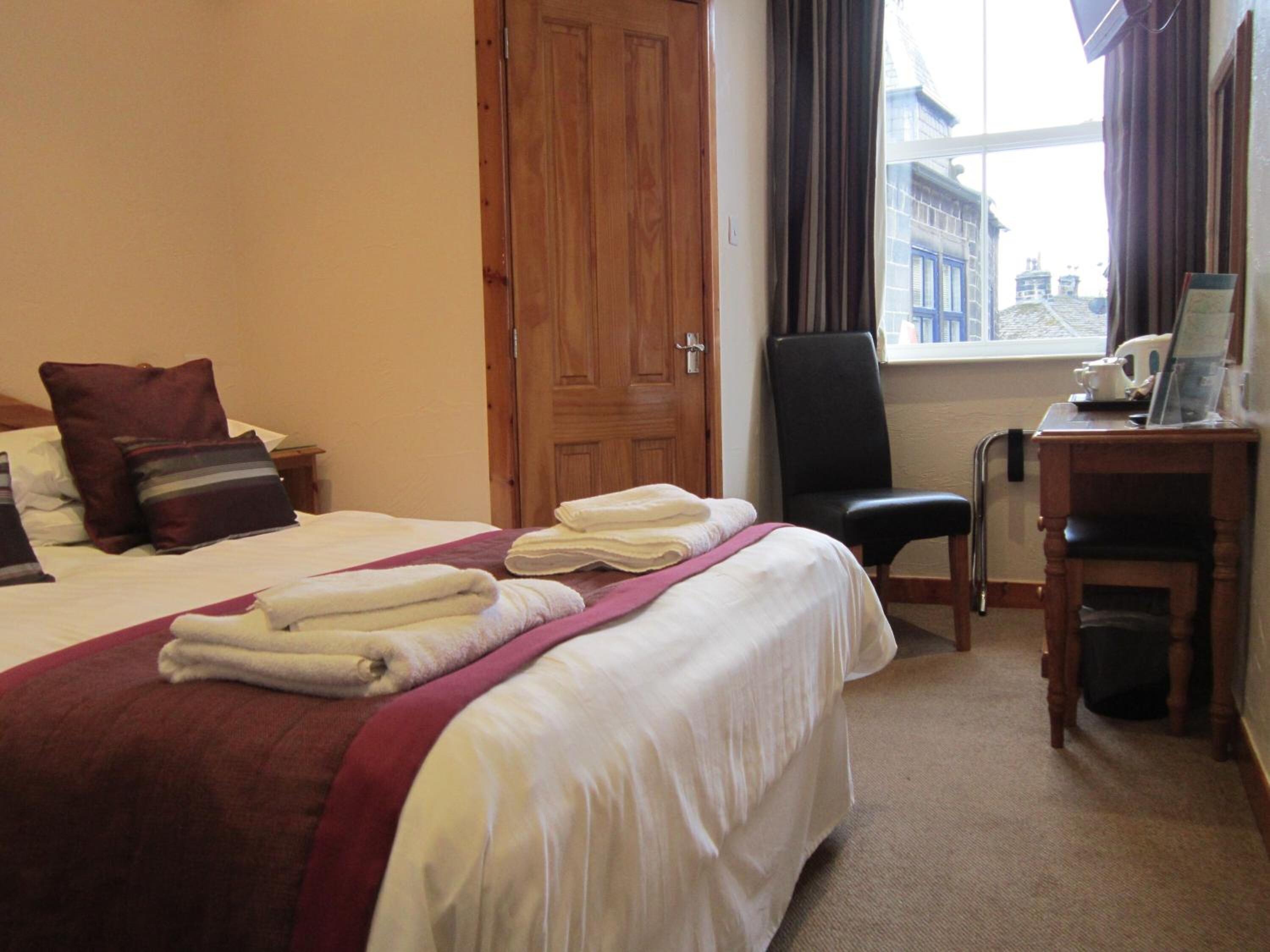 A hotel room with a bed, a desk, and a chair.
