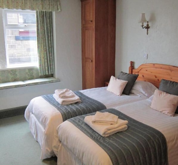 A double bed with a wooden headboard, two pillows, and folded towels on each side.